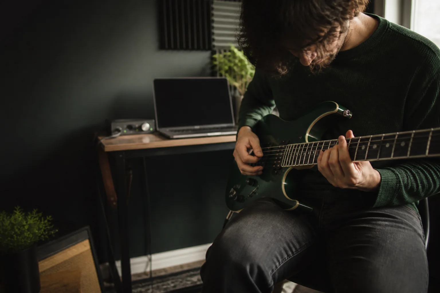 A guitarist using a home practice setup to work on an electric guitar part